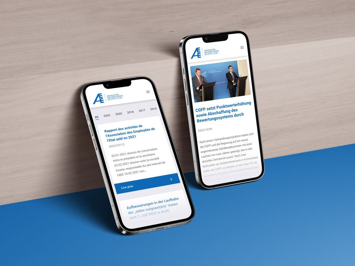 Two iPhones leaning against a wooden surface showing the news overview and a single news article.