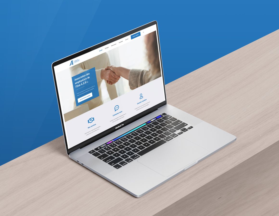 MacBook auf Holzuntergrund mit blauem Hintergrund, der die Homepage der AEE ASBL-Website zeigt.