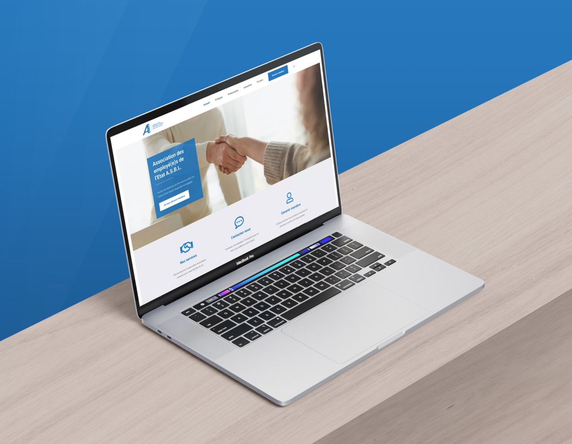 MacBook on wooden background with blue background showing the homepage of the AEE ASBL website.