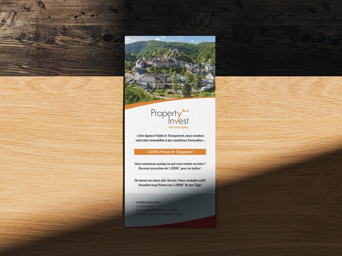 Vorderseite des DL-Flyers von Property Invest Nord, präsentiert auf einem Holztisch.