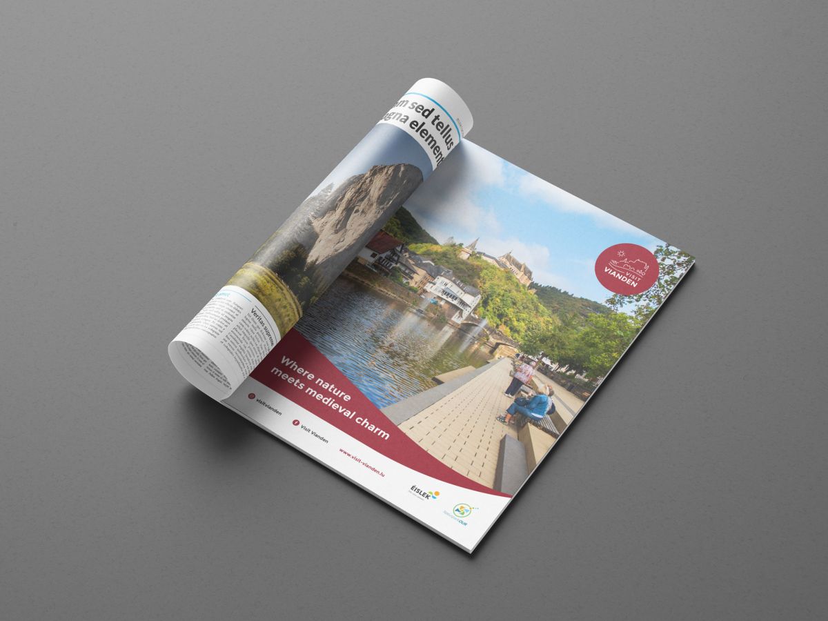 Din A4 große Anzeige für Visit Vianden, die die Promenade, den Fluss, die Brücke und das Schloss zeigt.