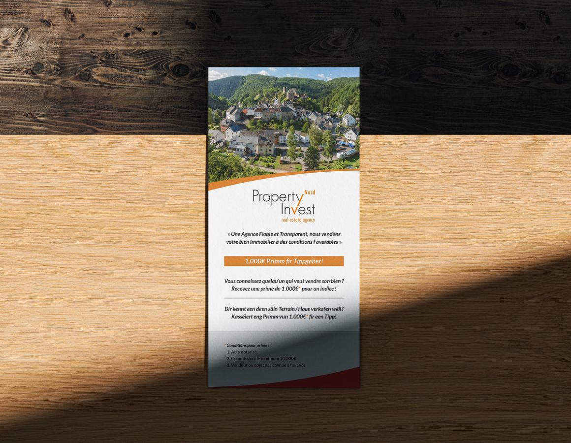 Vorderseite des DL-Flyers von Property Invest Nord, präsentiert auf einem Holztisch.